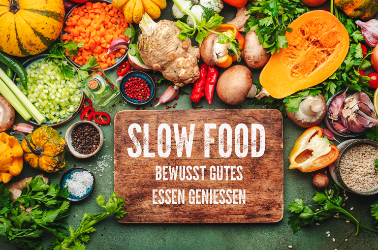Viel frisches Gemüse um ein mit SLOW FOOD beschriftetes Brettchen