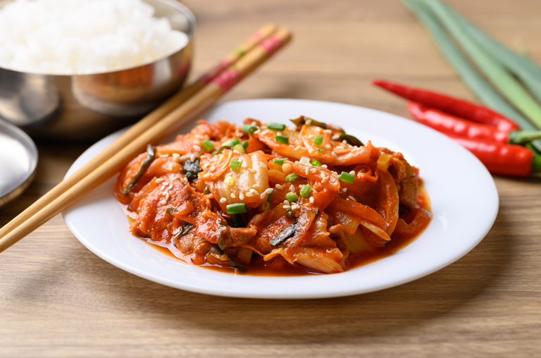 Kimchi auf einem Teller mit Sesam und Stäbchen