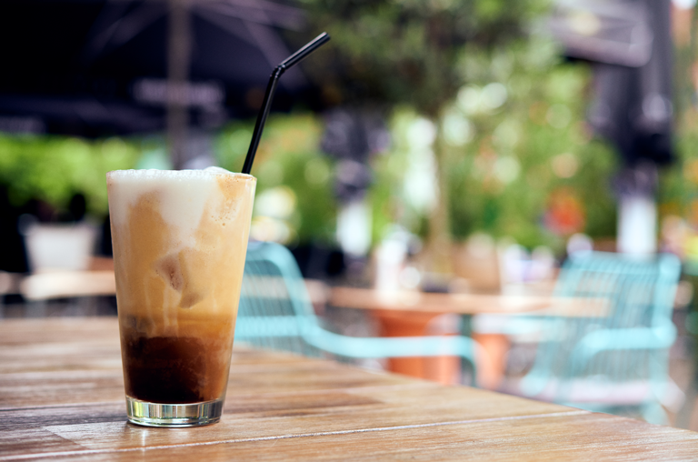 Das Aufmacherbild zum Thema Eiskaffee und Eistee für EDEKA Nils Meyer zeigt einen Eiskaffee im Glas auf einem Holztisch in einem Café im Sommer