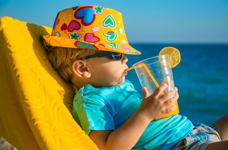 Kind mit Cocktail am Strand